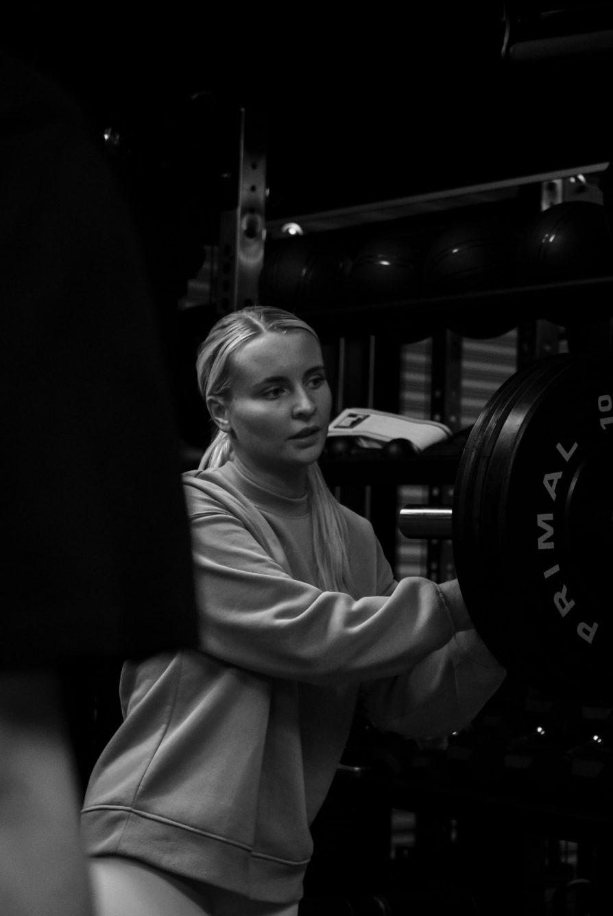 Xceed Glasgow member loading plates onto a barbell rack